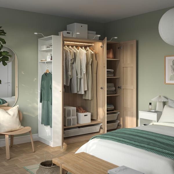 Bedroom with open wooden wardrobe displaying clothes and storage.