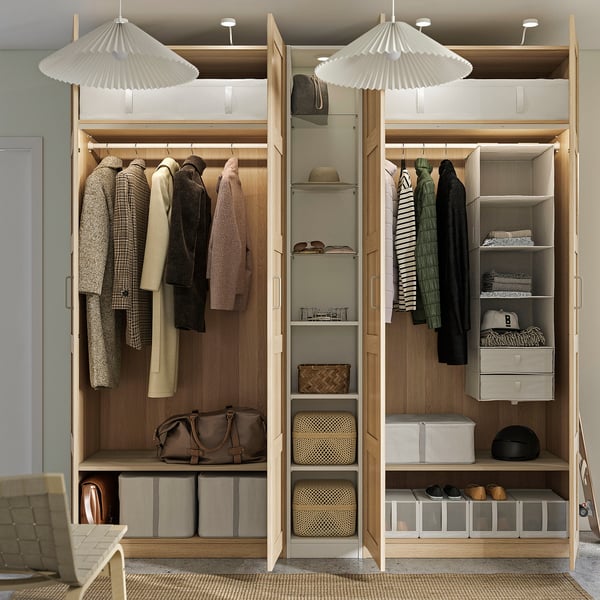 Well-organized wooden wardrobe with hanging clothes, shelves, and storage bins. Adjustable lighting above.