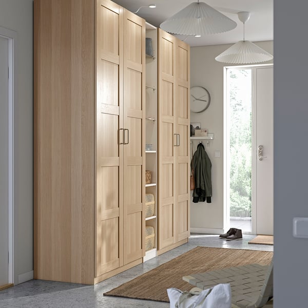 Modern entryway with light PAX wardrobe, open doors showing shelves, coat hooks, jute rug, pendant lights.