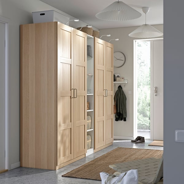 Large light wood PAX wardrobe by entry, tall with multiple compartments for storage, minimalist design.