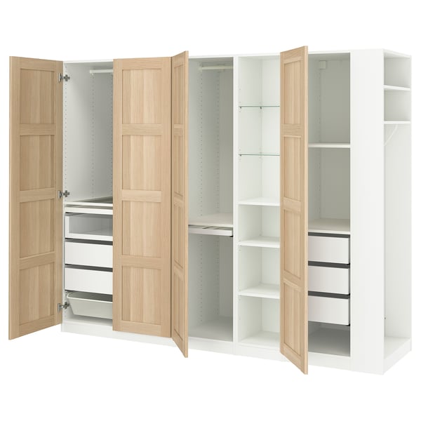 An open, white IKEA PAX wardrobe with light wood doors, featuring shelves and drawers.