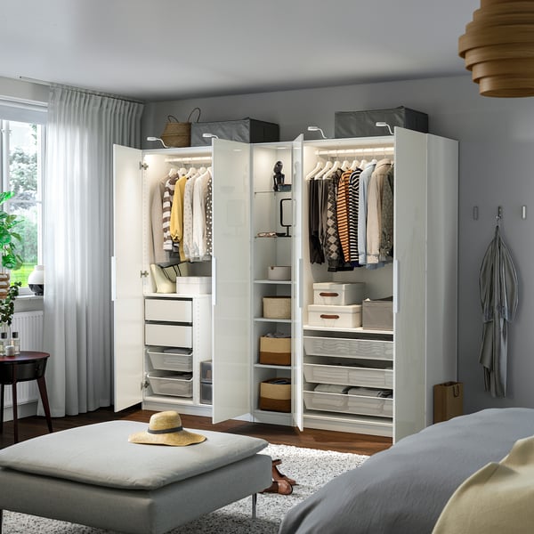 Modern wardrobe with organised clothes and storage boxes, integrated lighting, and a stool with a hat.