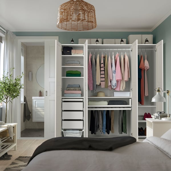 Bedroom with PAX wardrobe showcasing organised clothes, shelves, and drawers. A mirror and a lamp are also visible.