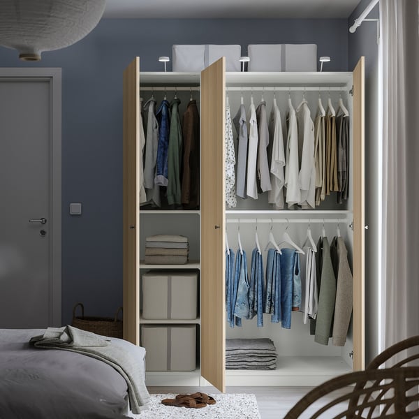 Open wardrobe with clothes and storage boxes, showing internal organisation with hanging rails and shelves.