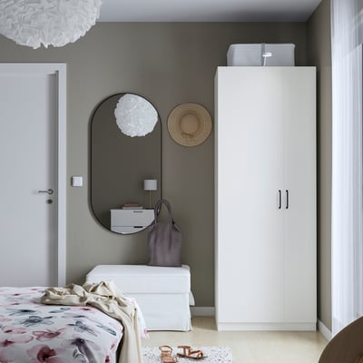 Modern bedroom with a white corner PAX wardrobe, large mirror, and floral bedspread.