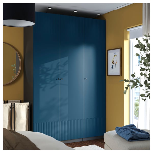 Modern bedroom with large blue PAX wardrobe, bed, and plant.
