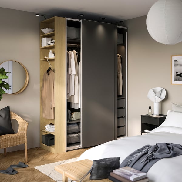 Modern bedroom featuring a PAX wardrobe with sliding doors, showcasing organised hanging clothes, shelves, and storage solutions.
