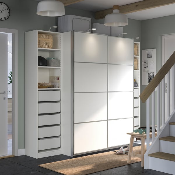 Modern hallway with white PAX wardrobe, shelves, and stairs, featuring sleek storage and minimalist design.