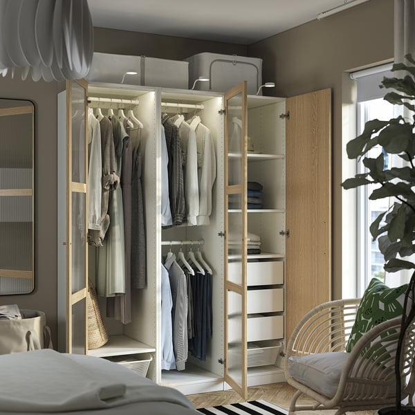 Modern open wardrobe showing clothes, shelves, and drawers. Soft-closing hinges visible. Integrated lighting illuminates interior.