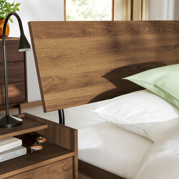 Bed frame with headboard,decorative lamp,books,pillows.