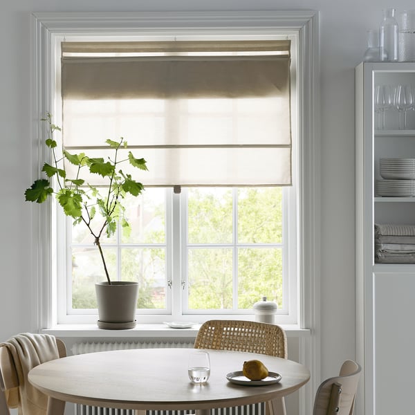 Modern dining area with RINGBLOMMA blind, round table, chairs, lemon, glass, plant, and shelves with dishes and glasses.