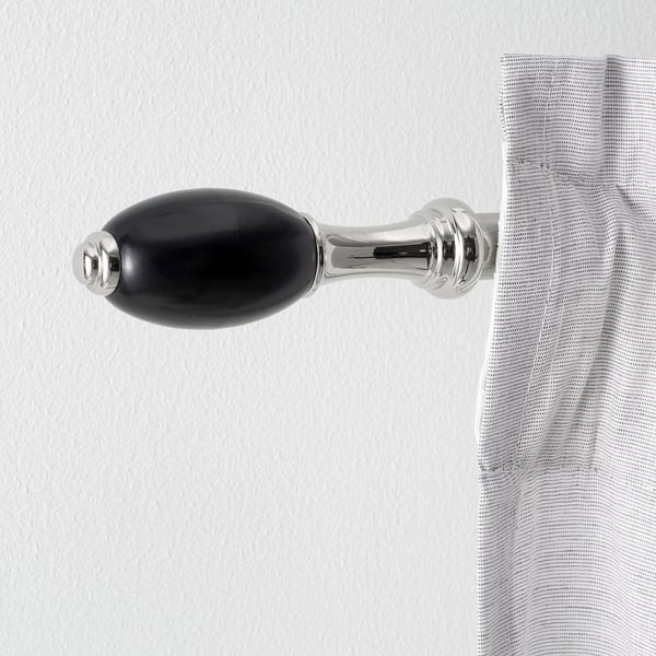 Black and silver curtain rod bracket with shiny finish on wall holding striped curtain.