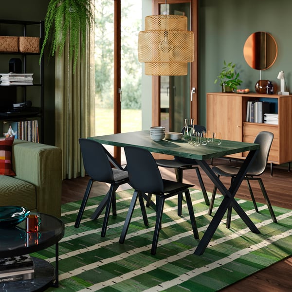 Modern dining area with SKÅLSTA table, black, rectangular, surrounded by black chairs. Rugged, stylish design; earthy tones match decor.