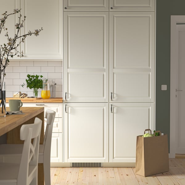 Modern kitchen with TINAD fridge, white cabinets, wooden counter, chairs, and items. Integrated fridge fits between cabinets.