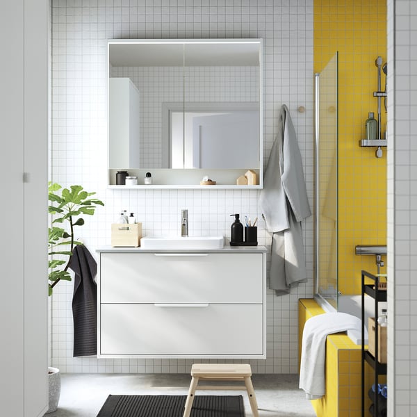Modern bathroom with TOLKEN white countertop; sleek, rectangular vanity, large mirror, gray towels.