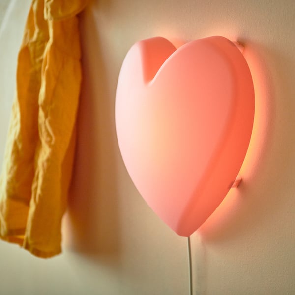 Heart-shaped pink wall lamp for kids. Made of recycled plastic, emits soft light.