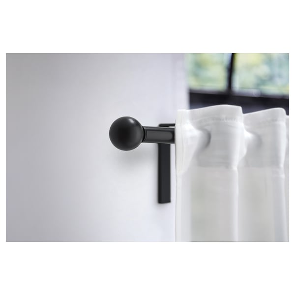Black spherical curtain finial, simple modern design. Made from recycled plastic, mounted on wall.