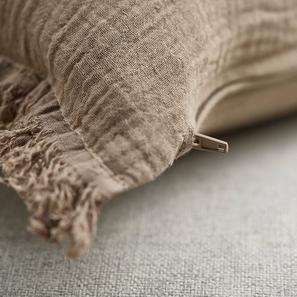 Soft, beige cushion cover with zip, made from 100% cotton muslin, featuring crinkled texture and raw edges for a casual look.