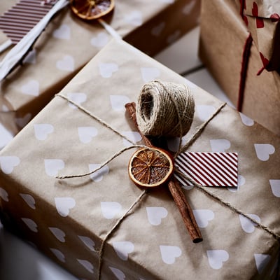 Gift wrapped in brown paper with white hearts, adorned with dried orange slice and twine.
