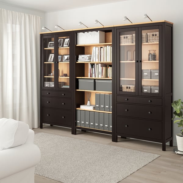 Современная гостиная с шкафом для хранения HEMNES, стеклянными дверями, ковром и шторами.
