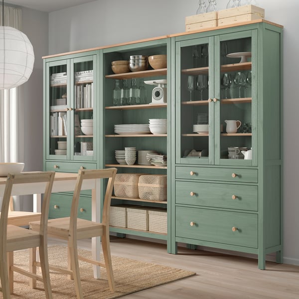 Зеленый шкаф для хранения HEMNES, стеклянные двери, деревянные полки, миски, посуда, бокалы для вина, книги, стулья.