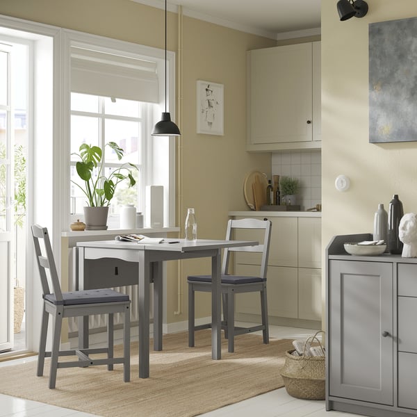 Уютная обеденная зона с современным серым столом и стульями в тон, большим окном, бежевым ковром и декором.