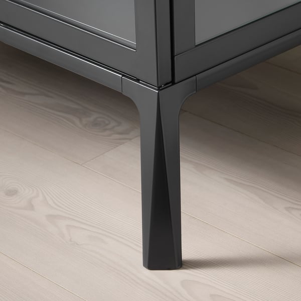 Черный металлический шкаф с угловой ножкой на деревянном полу.
