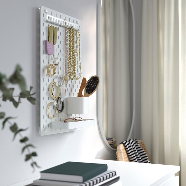 Настенная доска SKÅDIS с ювелирными изделиями, щетками и аксессуарами, демонстрирующими организационную функцию.