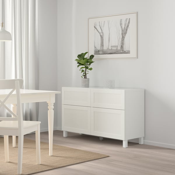 White BESTÅ sideboard with 2 drawers near dining table & chairs, plant, bright room.