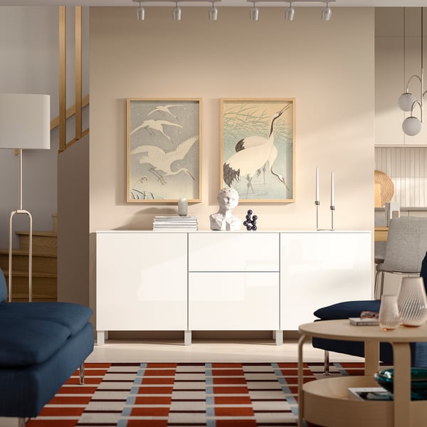 BESTÅ sideboard with crane paintings, colourful rug, blue seating, wood table with books.