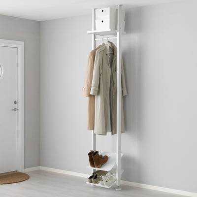 A white ELVARLI storage system with shelves and a clothes rail. Its tall, holding coats and boots, placed beside a white door.