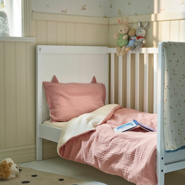 Cosy kids bed with pink GULDVÄVARE bedding; stuffed animals; small book.
