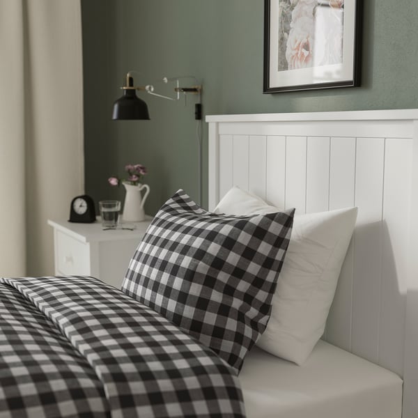 A modern bedroom featuring a traditional GULLABERG bed frame with a black and white chequered bedspread against a white headboard.