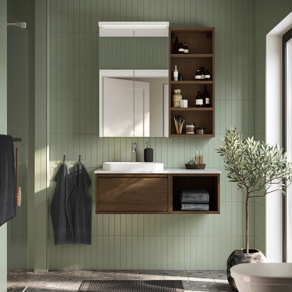 Modern green bathroom with HAGAÅN wooden cabinet, mirror, sink, towels, and plant.
