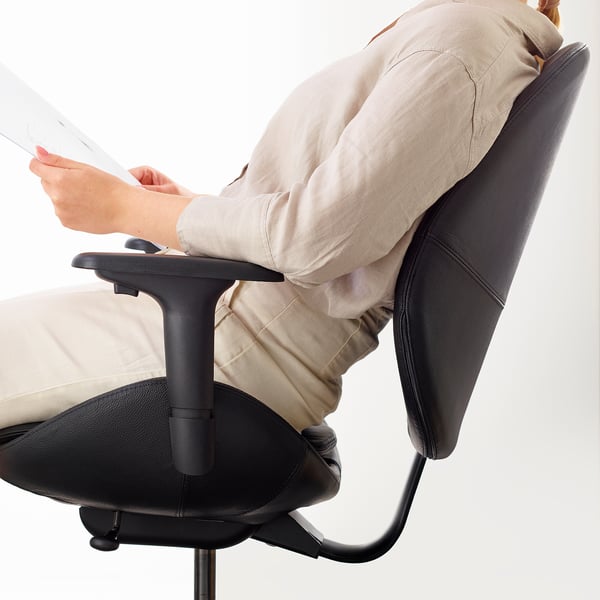 Person sitting on ergonomic office chair, reading documents.