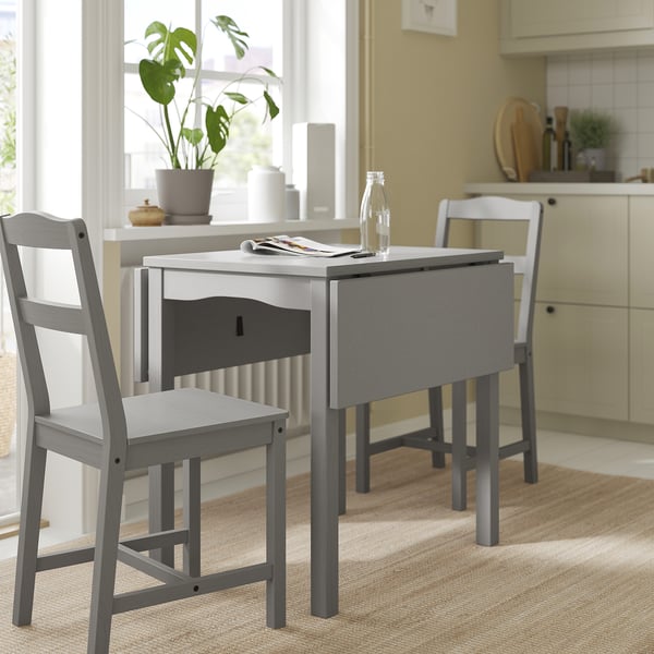 Minimalist kitchen setup with grey HAUGA drop-leaf table and chairs. Compact design, wooden material, and modern aesthetic.