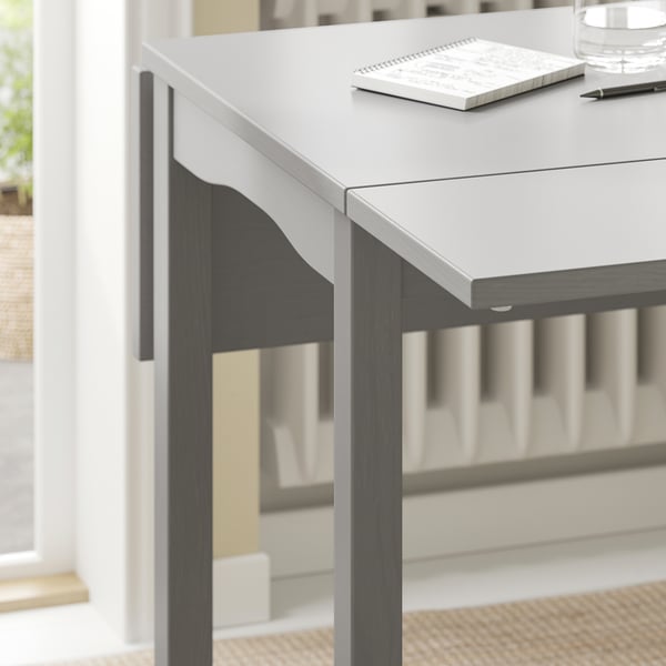 HAUGA drop-leaf table in grey and black wood. Rectangular top with scalloped edges, metal pen, and notebook.