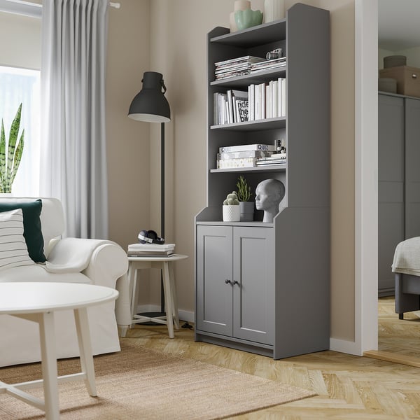 Modern living room with HAUGA grey bookshelf, white couch, black lamp, and wooden floor.