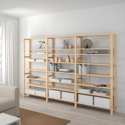 Large wooden IVAR shelves hold books and decor near a window, exceeding couch height.