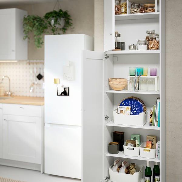 Open white kitchen cabinet showing organised items: jars, bowls, cups, and boxes.
