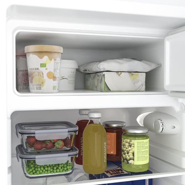 Open refrigerator with items: strawberries, peas, juice, and ice cream. Adjustable glass shelves visible.