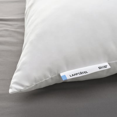 Close-up of a white pillow labelled LAPPTÅTEL by IKEA, exhibiting soft, high-quality microfibre fabric, resting on a bed.