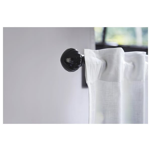 Black ceramic finial on white curtain, modern decor detail