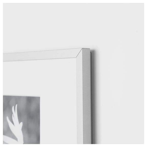 Close-up of silver frame corner, blurred hand reaching out.
