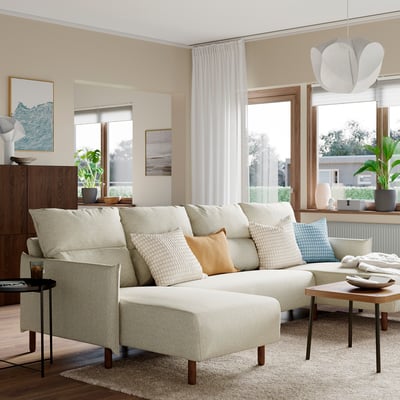 Modern living room with cream MANNARP sofa, windows, side tables, and plant.