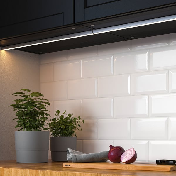 Modern kitchen counter with integrated led lights, plants, and onions. The lights enhance task efficiency and ambiance.