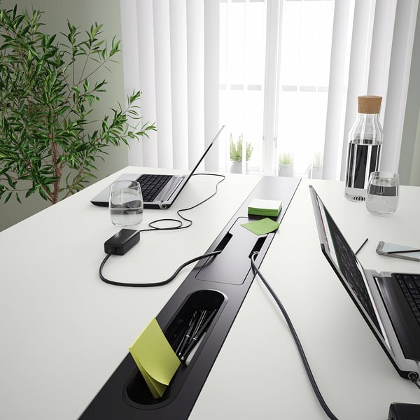 Modern conference table with integrated cable management and footrest, perfect for sitting or standing meetings.
