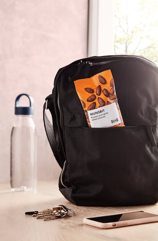 Backpack with orange packaged snack labelled MUNSBIT on a table near keys and phone.