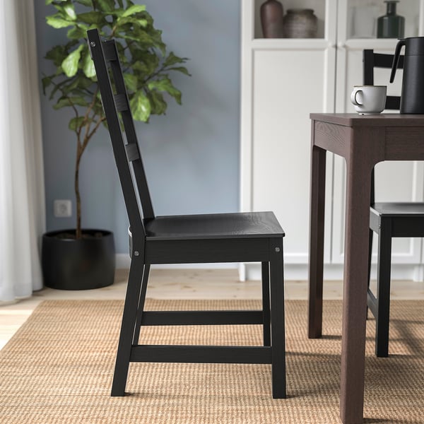 Black wooden chair with high backrest near wooden table on rug.