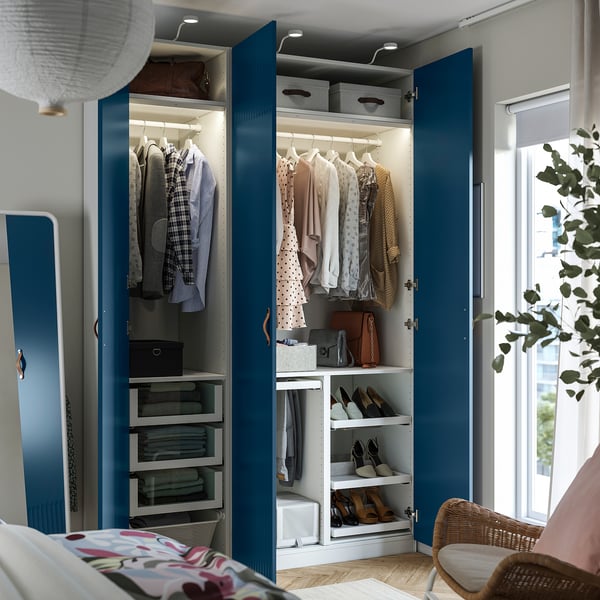 Open blue wardrobe with clothes, shelves, drawers, and lighting.